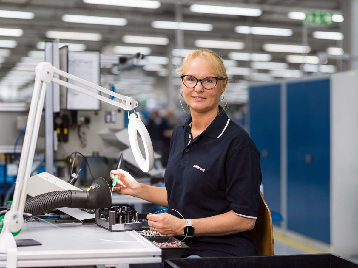 Businessfotografie Industrie und Fotografie: Mitarbeiterin in moderner Produktionshalle bei präziser Montagearbeit mit technischer Ausrüstung in Düsseldorf